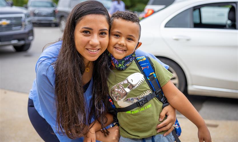 A mother and son smile after arriving to school